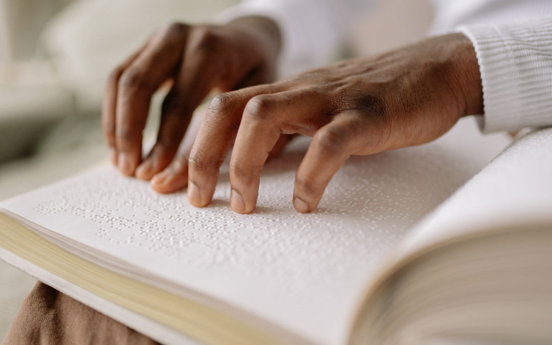 mãos negras tateando as letras em braile de um livro